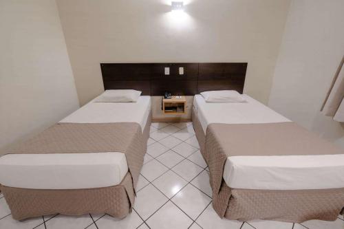two beds in a small room with at Hotel Caiuá Express Umuarama in Umuarama
