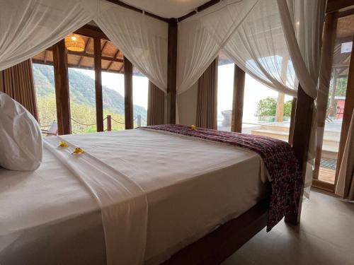 a bed in a room with a large window at Amed Hill Ocean View in Ambat
