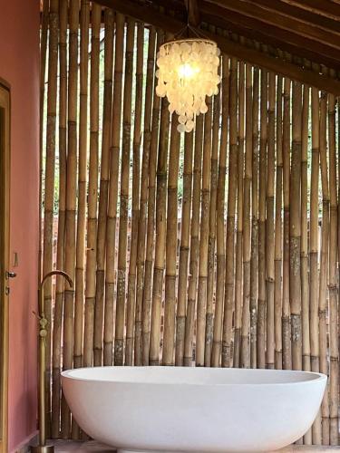 a bathroom with a white tub and a bamboo wall at Amed Hill Ocean View in Ambat