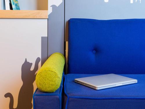 a blue chair with a laptop and a pillow at Aparthotel Adagio access Montpellier Centre in Montpellier