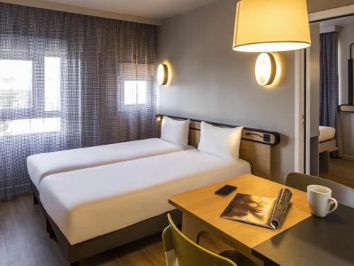 a hotel room with a bed and a desk with a table sidx sidx at Aparthotel Adagio access Montpellier Centre in Montpellier