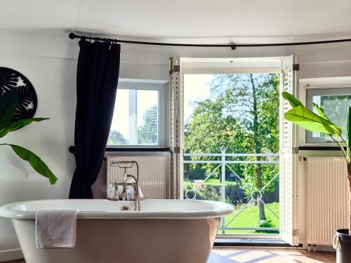 a bath tub in a bathroom with a window at Hajé Hotel Restaurant de Lepelaar in Lelystad