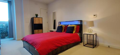 Un dormitorio con una cama roja con una manta roja. en Luxury CITY Apartment, en Watford