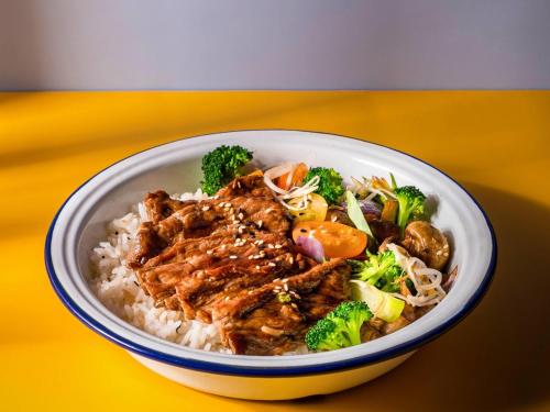 a bowl of food with rice and broccoli on a yellow table at Pullman Santiago El Bosque in Santiago