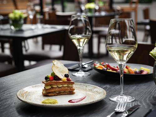 a table with a plate of food and two glasses of wine at Pullman Santiago El Bosque in Santiago