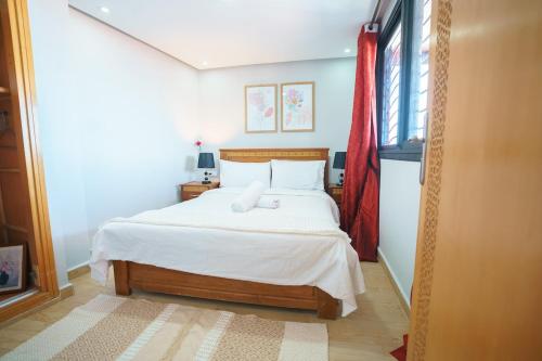 Un dormitorio con una cama con sábanas blancas y una ventana. en Ocean Vibes Sea View and Fast Wi-Fi, en Tánger