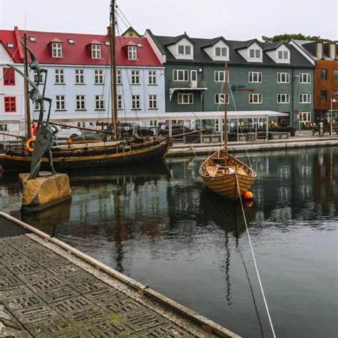 two boats are docked in the water in front of buildings at Modern Apartment with Balcony & Stunning Views in Argir