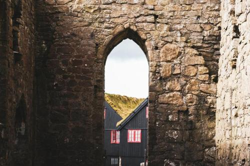 an arch in a stone wall with a black building at Modern Apartment with Balcony & Stunning Views in Argir
