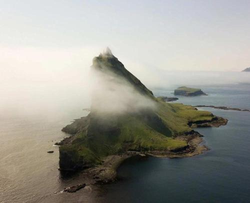 an island in the ocean with fog on it at Modern Apartment with Balcony & Stunning Views in Argir