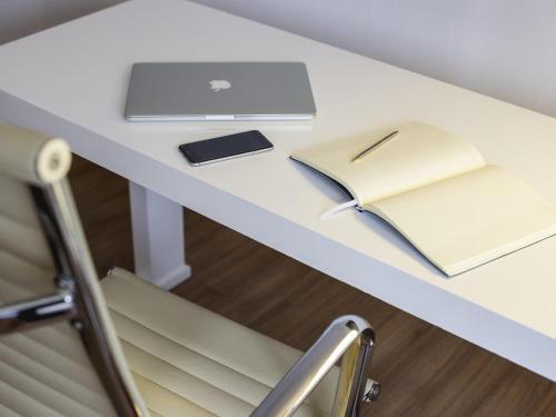 a desk with a laptop and a notebook on it at Novotel Bogota Parque 93 in Bogotá