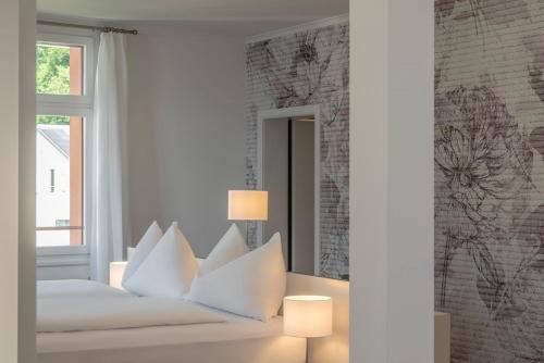 a bedroom with a white bed with pillows and a mirror at Hotel Vitznauerhof - Lifestyle Hideaway at Lake Lucerne in Vitznau
