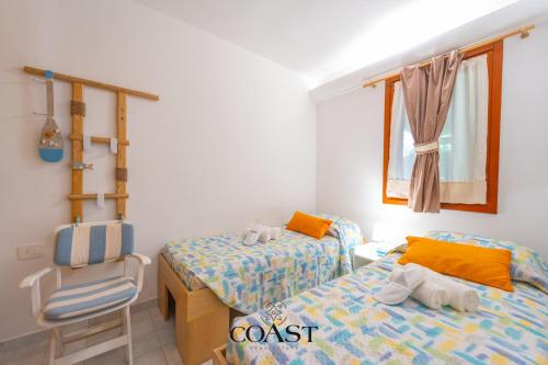 a bedroom with two twin beds and a chair at Giardino sul Mare - Elegante Appto con Wi-Fi e AC in Marina di Portisco