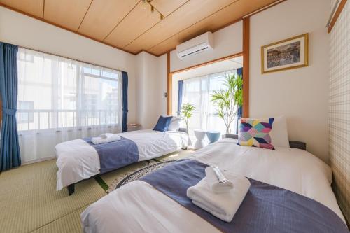 twee bedden in een kamer met een raam bij TDR車9分 3BR 5Bed 夢の続きを楽しめる宿 -TAMU-LAND Kasai- in Tokyo