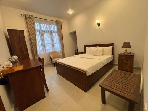 une chambre avec un lit, une table et un bureau dans l'établissement Collingwood Queen - Boutique Hotel, à Nuwara Eliya