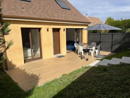 a wooden deck with a table and an umbrella at Maison au Pays de Fontainebleau in Vulaines-sur-Seine