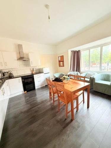 a kitchen and living room with a table and chairs at Large 4 Bedroom Sleeps 8, Spacious Apartment for Contractors and Holidays near Bedford Centre - 1 FREE PARKING SPACE & FREE WIFI in Bedford