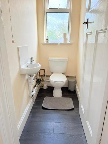 a bathroom with a toilet and a sink and a window at Large 4 Bedroom Sleeps 8, Spacious Apartment for Contractors and Holidays near Bedford Centre - 1 FREE PARKING SPACE & FREE WIFI in Bedford