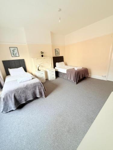 a room with two beds in a room at Large 4 Bedroom Sleeps 8, Spacious Apartment for Contractors and Holidays near Bedford Centre - 1 FREE PARKING SPACE & FREE WIFI in Bedford