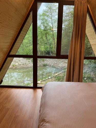 a bedroom with a bed and a large window at Cabana Vatra Râului in Lazuri