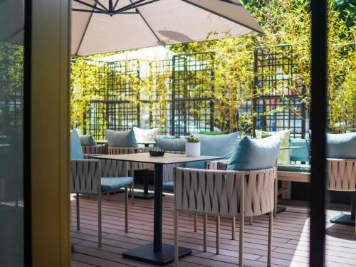 a patio with tables and chairs and an umbrella at Aparthotel Adagio Premium Casablanca City Center in Casablanca