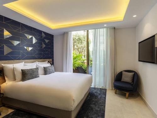 a bedroom with a large bed and a chair at Aparthotel Adagio Premium Casablanca City Center in Casablanca