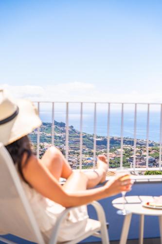 a woman sitting in a chair on a balcony at The Vinehill House in Câmara de Lobos