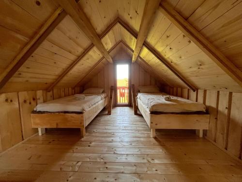 two beds in a wooden room with a window at Tree house - Ethno holistic village Apače in Apače