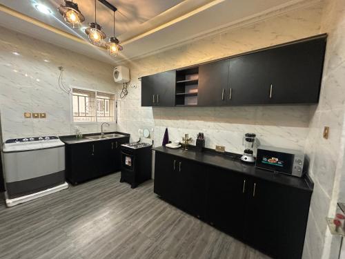 アブジャにあるLa Paz Palacio Homes & Apartments, Airport Road Lugbeの広いキッチン(黒いキャビネット、シンク付)