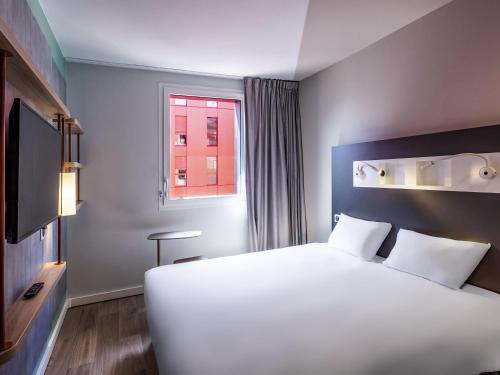 a bedroom with a large white bed and a window at ibis budget Saint-Étienne Centre Gare Châteaucreux in Saint-Étienne
