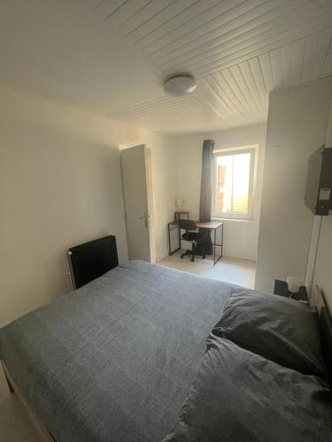 a bedroom with a bed and a desk and a window at 2 bedroom Apartment very close to Paris in Bobigny