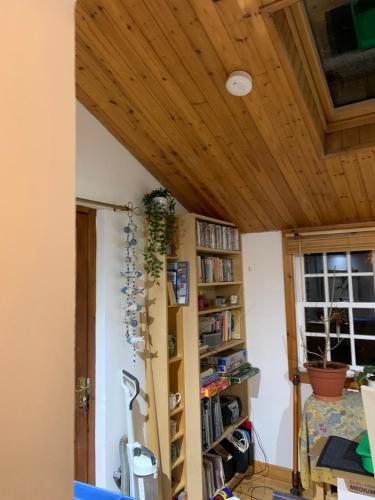 a room with a wooden ceiling and a book shelf at Cosy cottage flat in Inveraray