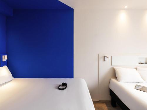 a bedroom with a white bed with a blue wall at ibis budget Aguascalientes Norte in Aguascalientes
