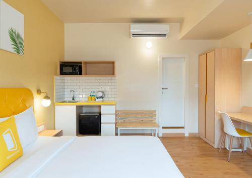 a bedroom with a white bed and a kitchen at Bloom Hotel Financial District in Hyderabad