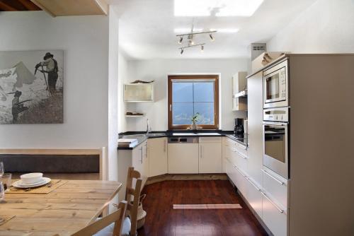 a kitchen with white cabinets and a table and a window at Zillertalblick in Zell am Ziller