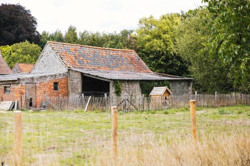 an old brick building in a field next to a fence at Tiny House Natuur & cultuur nabij Brugge! in Beernem