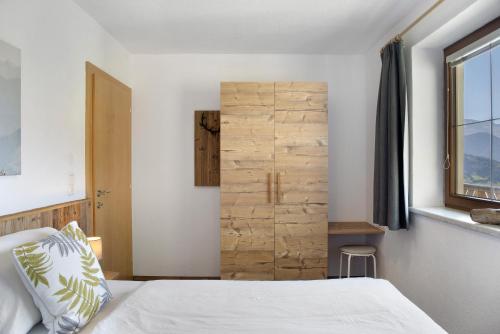 a bedroom with a bed and a wooden wall at Zillertalblick in Zell am Ziller