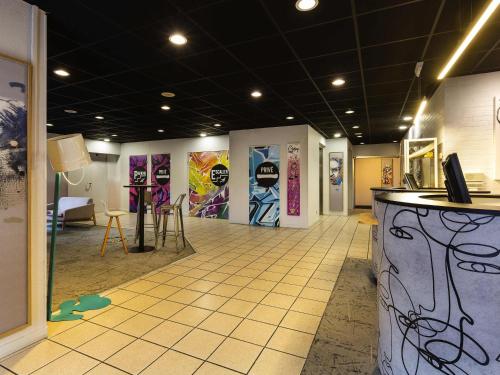 a room with a counter and paintings on the walls at Ibis Styles Toulouse Centre Canal du Midi in Toulouse