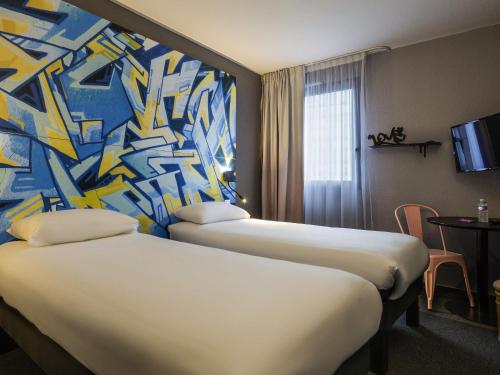 two beds in a hotel room with a painting on the wall at Ibis Styles Toulouse Centre Canal du Midi in Toulouse