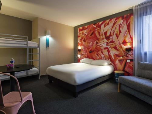 a bedroom with a bed and a large painting on the wall at Ibis Styles Toulouse Centre Canal du Midi in Toulouse