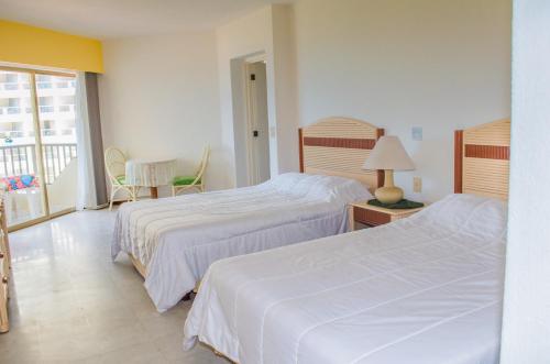イスタパにあるENNA INN IXTAPA DEPARTAMENTO 01 RECAMARA ViSTA MARのベッド2台とバルコニーが備わるホテルルームです。