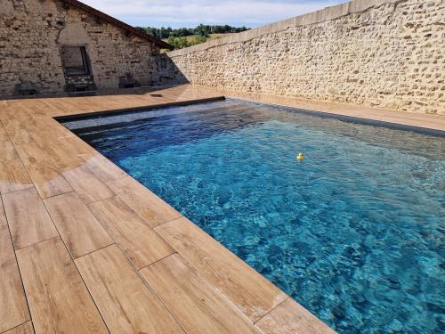 a swimming pool next to a brick wall at Hameau Grande Varenne - Gites de charme avec piscine in Charroux-dʼAllier