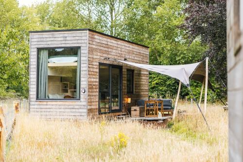 a small brick house with a tent in a field at Tiny House in the Nature of Bruges in Beernem
