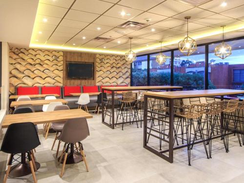 a dining room with tables and chairs and windows at ibis Cucuta in Cúcuta
