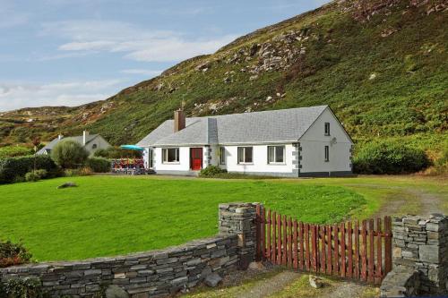 a white house with a fence in front of a hill at 4 Bed in Clifden oc-i243 in Belleek