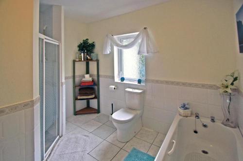 a bathroom with a toilet and a tub and a window at 4 Bed in Clifden oc-i243 in Belleek
