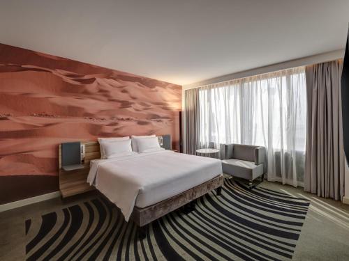 a bedroom with a bed and a large painting on the wall at Novotel Sharjah Expo Centre in Sharjah
