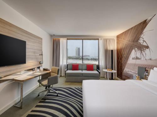 a hotel room with a bed and a desk with a computer at Novotel Sharjah Expo Centre in Sharjah