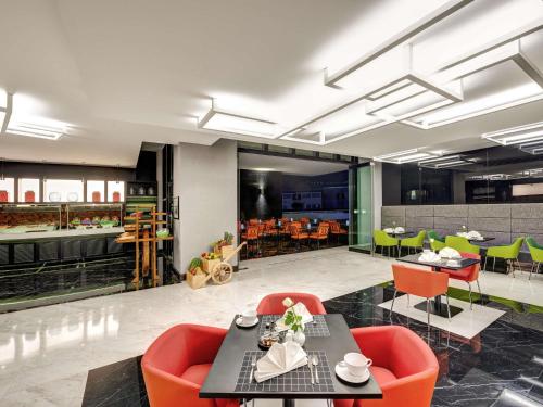 a dining room with orange chairs and tables in a building at Novotel Sharjah Expo Centre in Sharjah