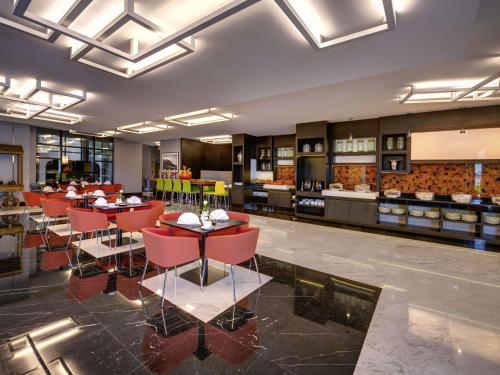 a restaurant with red chairs and tables in a room at Novotel Sharjah Expo Centre in Sharjah