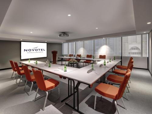 a conference room with a long table and chairs and a screen at Novotel Sharjah Expo Centre in Sharjah